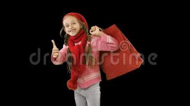 一个扎着辫子、戴着红色针织帽子和围巾的小女孩带着购物袋或礼物，把它们扔到自己身上